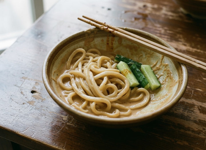 Peanut rayu sesame noodles, thick udon in peanut sauce with cucumber, half eaten